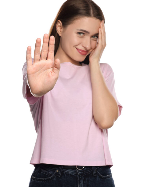 Embarrassed young woman covering face with hand on white background - Foto, Bild