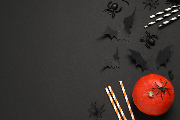 Flat lay composition with pumpkin, paper bats, spiders and cocktail straws on black background, space for text. Halloween decor - Foto, Bild