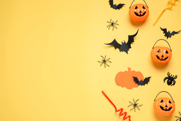 Flat lay composition with paper bats, plastic pumpkin baskets, spiders and cocktail straws on yellow background, space for text. Halloween decor - 写真・画像