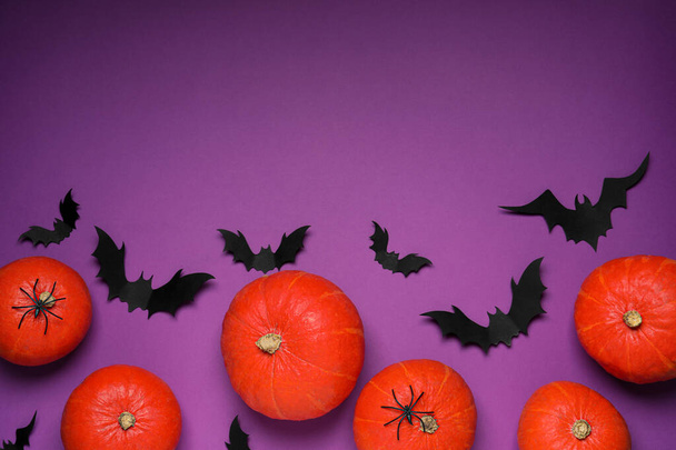 Flat lay composition with black paper bats and pumpkins on purple background, space for text. Halloween celebration - Foto, Bild