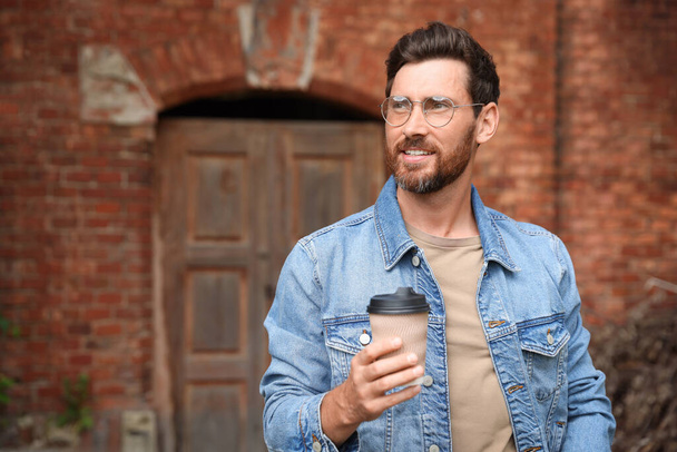 Handsome bearded man with paper cup outdoors. Space for text - Фото, зображення