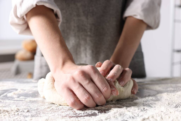 Woman kneading dough at table in kitchen, closeup - Фото, зображення