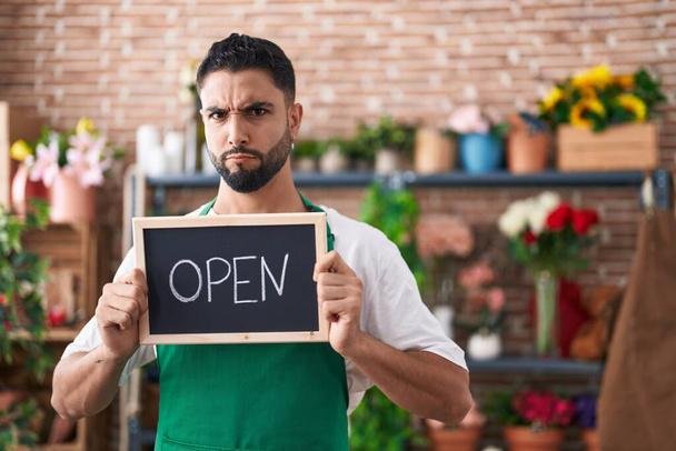 Hispanic young man working at florist holding open sign skeptic and nervous, frowning upset because of problem. negative person.  - Photo, Image