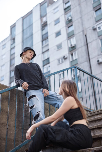 Teenagers hang out in the urban exterior on the stairs surrounded by the buildings. - Photo, Image