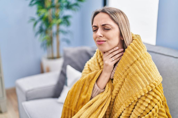 Giovane donna che soffre di mal di gola seduta sul divano a casa - Foto, immagini