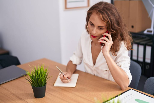 若い美しいパニック女性のビジネスワーカーは、オフィスでノートパソコンで書く上で話す - 写真・画像
