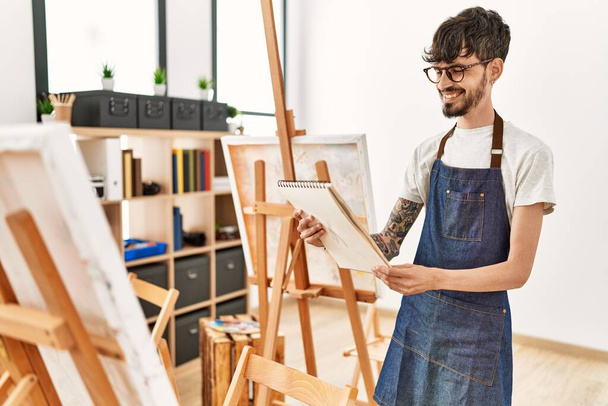 Jovem artista hispânico homem sorrindo desenho feliz no estúdio de arte. - Foto, Imagem