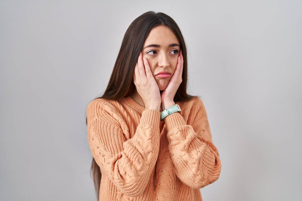 Young brunette woman standing over white background tired hands covering face, depression and sadness, upset and irritated for problem  - Photo, Image