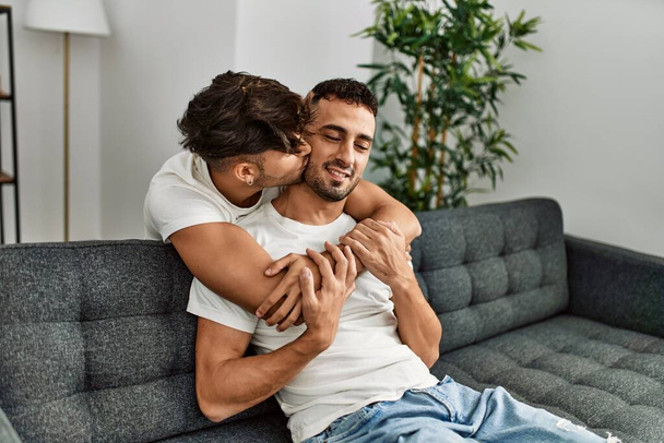 Kaksi latino miehet pari hymyilee luottavainen ja halaavat toisiaan kotona - Valokuva, kuva