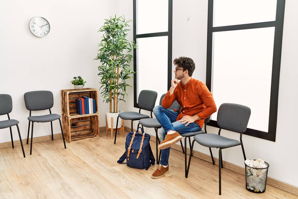 Νεαρός Ισπανός βαρετός κάθεται στην καρέκλα στην αίθουσα αναμονής - Φωτογραφία, εικόνα