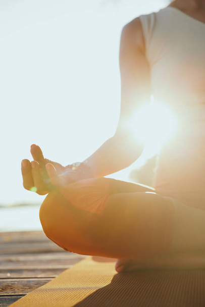 Close-up de uma mulher yogi sentado em uma pose de lótus e meditando. - Foto, Imagem