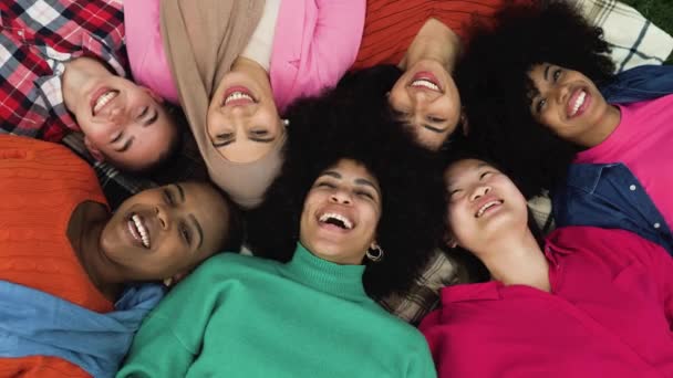 Ευτυχισμένες νεαρές πολυεθνικές γυναίκες που διασκεδάζουν ξαπλωμένες στο γρασίδι του πάρκου - Ποικιλομορφία και φιλία - Πλάνα, βίντεο