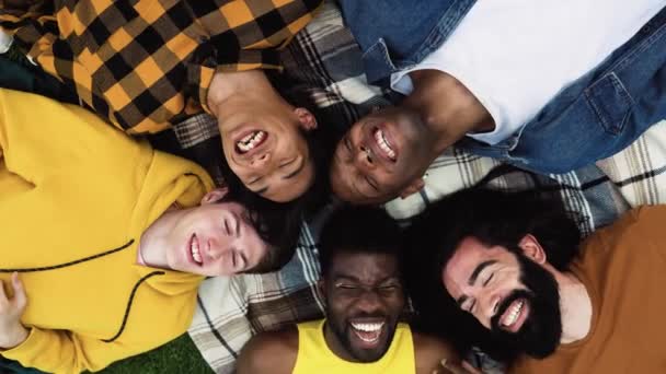 Vista superior de los jóvenes felices hombres multiétnicos divirtiéndose tumbados en la hierba del parque - Concepto de diversidad y amistad - Metraje, vídeo
