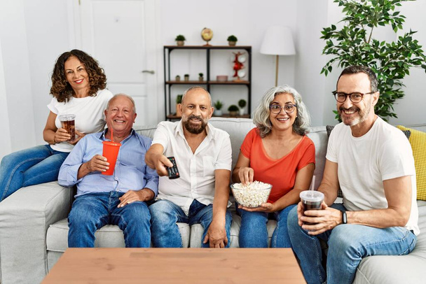 Group of middle age friends smiling happy watching film at home. - Фото, изображение