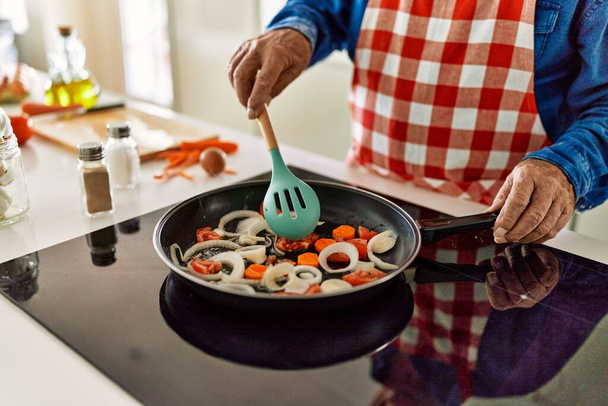Senior man cooking at kitchen - Фото, изображение