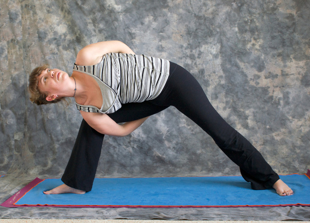 Женщина, занимающая позу йоги, удлиненный угол позы слева
 - Фото, изображение