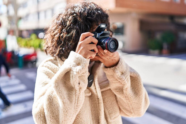 Jeune belle femme hispanique utilisant un appareil photo professionnel à la rue - Photo, image