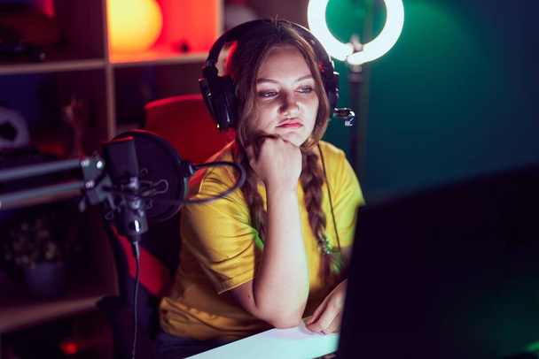 Joven mujer rubia streamer estresado utilizando la computadora en la sala de juegos - Foto, Imagen