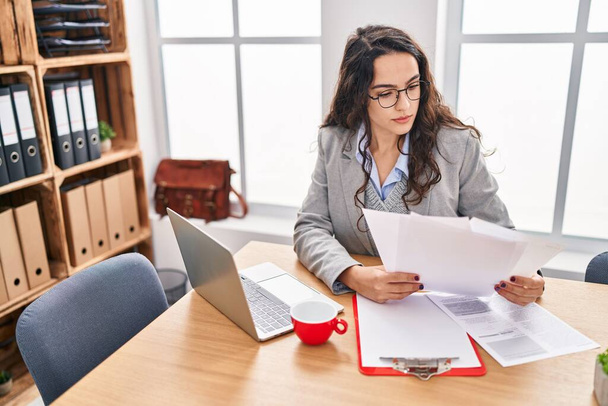 Młoda latynoska kobieta biznes pracownik czytanie dokument pracy w biurze - Zdjęcie, obraz