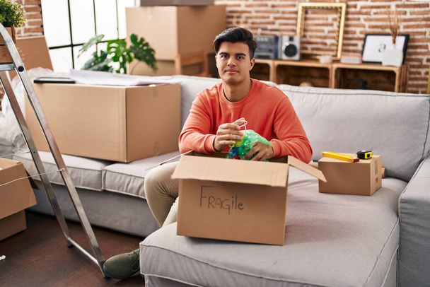 Hispanic man moving to a new home unpacking relaxed with serious expression on face. simple and natural looking at the camera.  - Photo, Image
