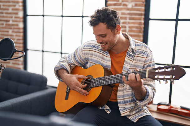 Mladý hispánec muž hudebník hraje na klasickou kytaru v hudebním studiu - Fotografie, Obrázek