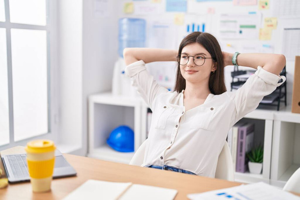 Young caucasian woman business worker relaxed with hands on head at office - Фото, зображення