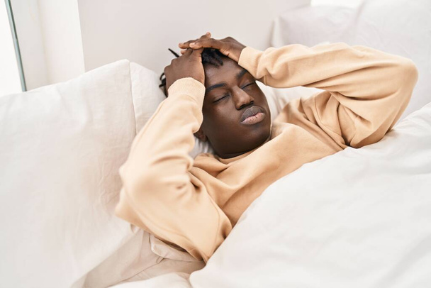 Αφροαμερικάνος άντρας στρεσαρισμένος στο κρεβάτι στην κρεβατοκάμαρα - Φωτογραφία, εικόνα
