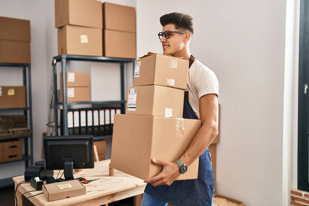 Young hispanic man ecommerce business worker holding packages at office - Photo, image