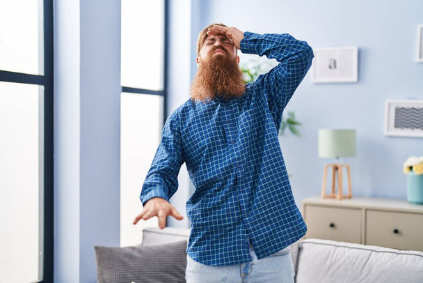 Nuori punapää mies kärsii huimausta seisoo kotona - Valokuva, kuva