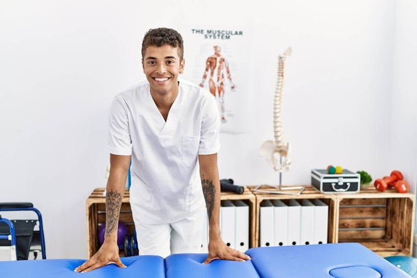 Młody Hiszpan pracuje jako fizjoterapeuta w pokoju fizjoterapii - Zdjęcie, obraz