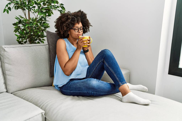 Fiatal afro-amerikai nő mosolyog magabiztos illatú csésze kávét otthon - Fotó, kép