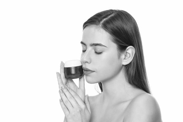 jonge vrouw houden crème pot voor gezicht huid geïsoleerd op witte achtergrond met kopieerruimte, reclame. - Foto, afbeelding