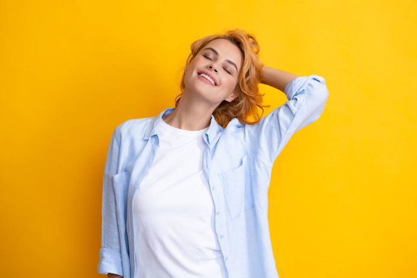 Femme rousse avec des cheveux de mouvement. Studio plan de rousse insouciante femme sourit joyeusement isolé sur fond jaune vif de bonne humeur - Photo, image