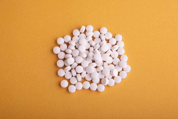 A pile of many white with medicine lying in a heap on a yellow background - Foto, immagini