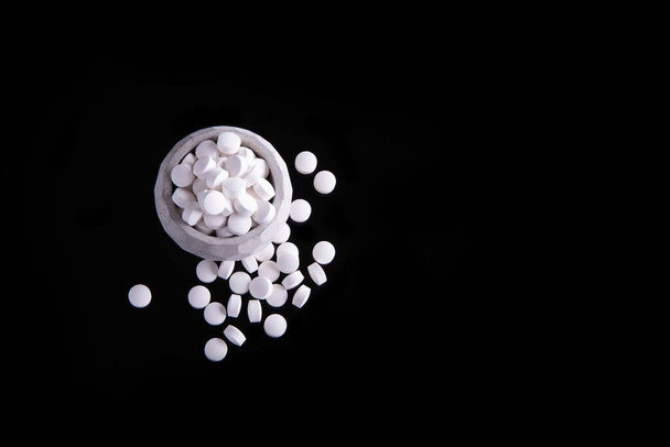 A pile of many white with medicine lying in a heap on a black background - Foto, Bild