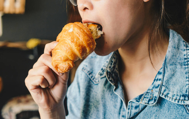 Cropped shot view of woman enjoy eating her breakfast with croissant. Conceptual shot of woman lifestyle when her hungry. - Фото, изображение