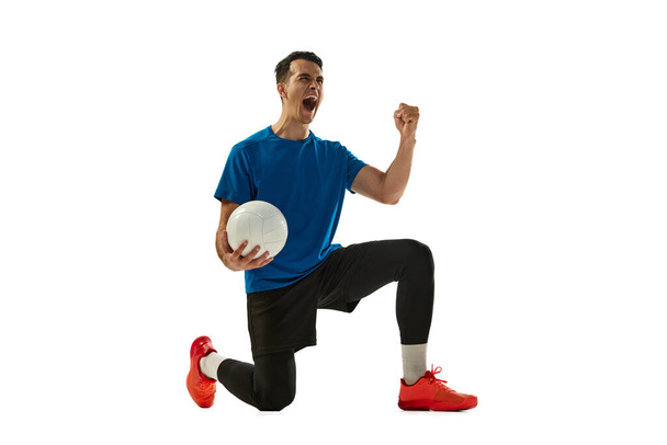 Studio shot of young man, volleyball player in sports uniform playing volleyball isolated on white studio background. Sport, gym, team sport, challenges. Copy space for ad - Valokuva, kuva