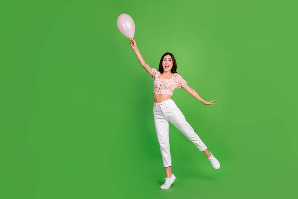 Full body size photo of young adorable pretty nice girl wear stylish outfit pink top hold air balloon excited carefree fly isolated on green color background. - Foto, imagen