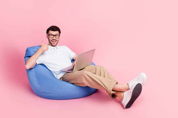 Photo of attractive man sit comfort chair satisfied quality modern technology devise gadget empty space isolated on pink color background. - Foto, Imagen