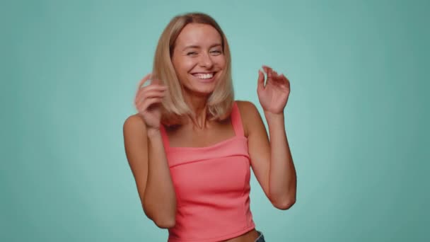 Szórakoztató boldog nő alkalmi termés tetején ujjal mutogatva a kamerára, hangosan nevetve, gúnyolódva a nevetséges megjelenésen, vicces vicc. fiatal lány pózol egyedül kék stúdió fal háttér - Felvétel, videó