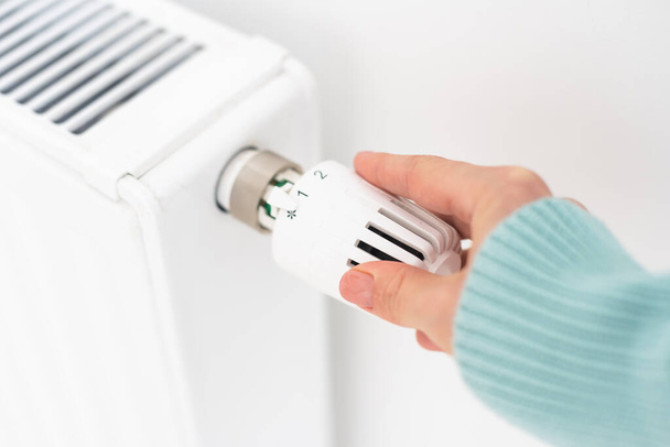 Womans hand on a white radiator. Heating season. Energy crisis. Cold batteries. Central heating. - Photo, Image