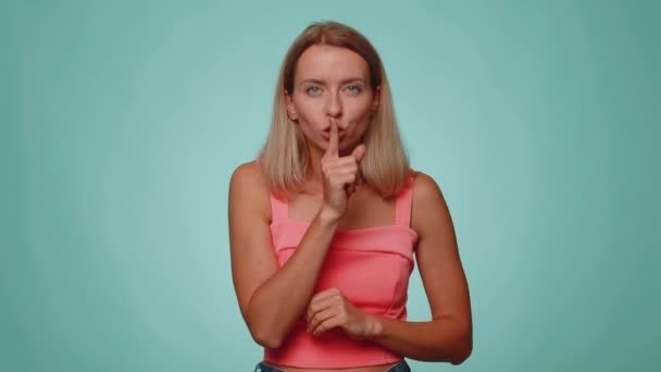 Cicho bądź proszę. Portret blondynki dorosłej kobiety 20 lat naciska palec wskazujący na usta sprawia, że znak gestu milczenia nie zdradza tajemnicy. młody dorosły ładna dziewczyna pozowanie na niebieski studio tło - Materiał filmowy, wideo