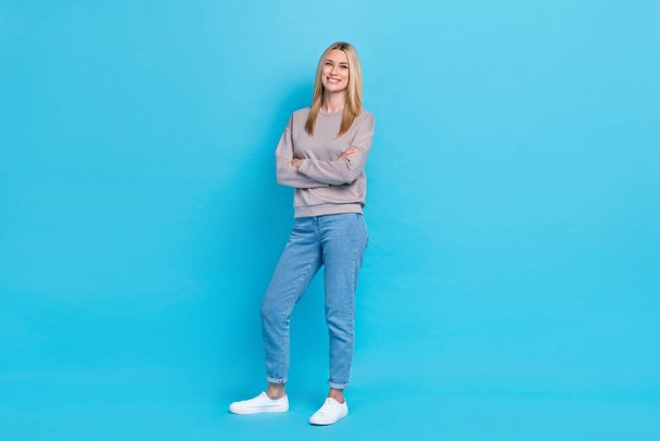 Full length photo of confident sweet lady wear grey sweatshirt standing arms folded smiling isolated blue color background. - Foto, afbeelding