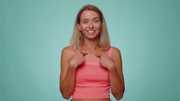 I choose you. Blonde pretty woman pointing to camera and looking with playful happy expression, making choice, showing direction. Young adult slim thin slender girl isolated on blue studio background - Footage, Video