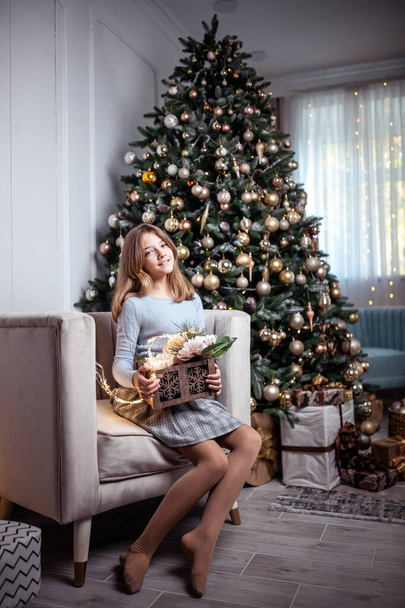 Menina adolescente bonito em um quarto com uma árvore de Natal decorada. As férias de inverno. Foto de alta qualidade - Foto, Imagem