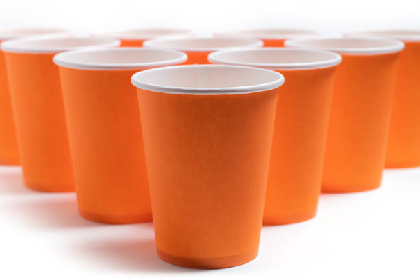 Большая группа оранжевых одноразовых бумажных стаканчиков. - Фото, изображение
