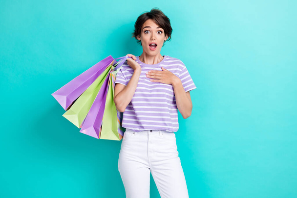 Photo of impressed cute girl dressed purple t-shirt rising shopping bags arm hand chest isolated teal color background. - Foto, imagen