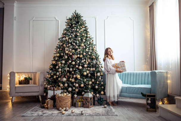 Aranyos tini lány egy szobában egy díszített karácsonyfával. A téli ünnepek. Kiváló minőségű fénykép - Fotó, kép