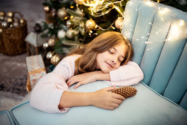 Menina adolescente bonito em um quarto com uma árvore de Natal decorada. As férias de inverno. Foto de alta qualidade - Foto, Imagem