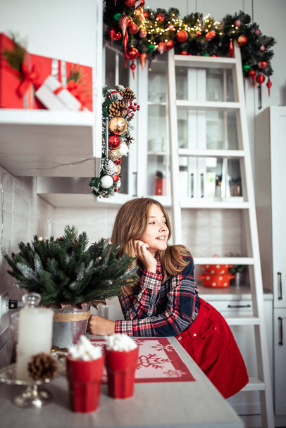 Linda adolescente en la cocina con decoraciones de Navidad. Las vacaciones de invierno. Foto de alta calidad - Foto, Imagen